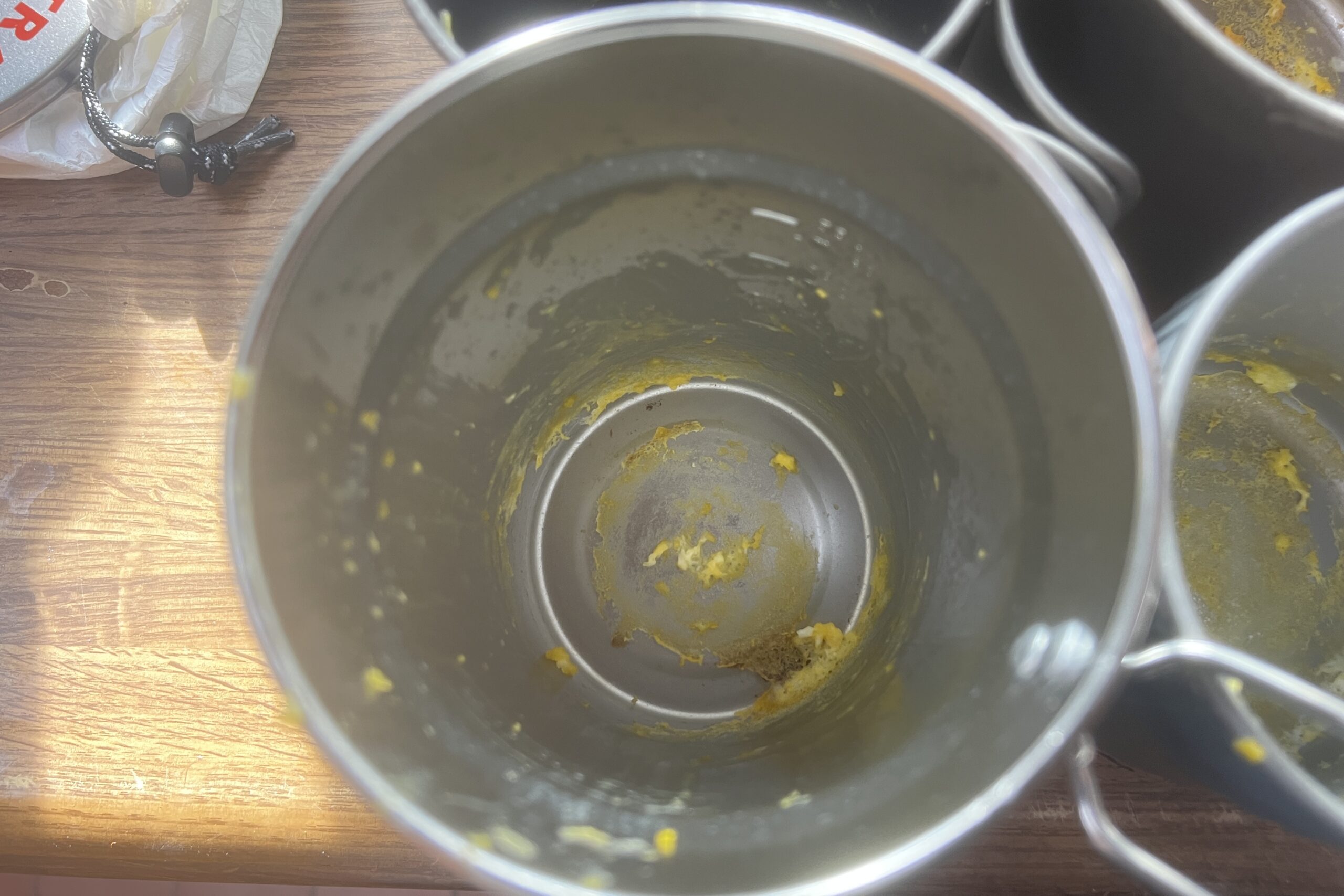 the inside of a stainless steel pot with remnants of scrambled egg left behind.