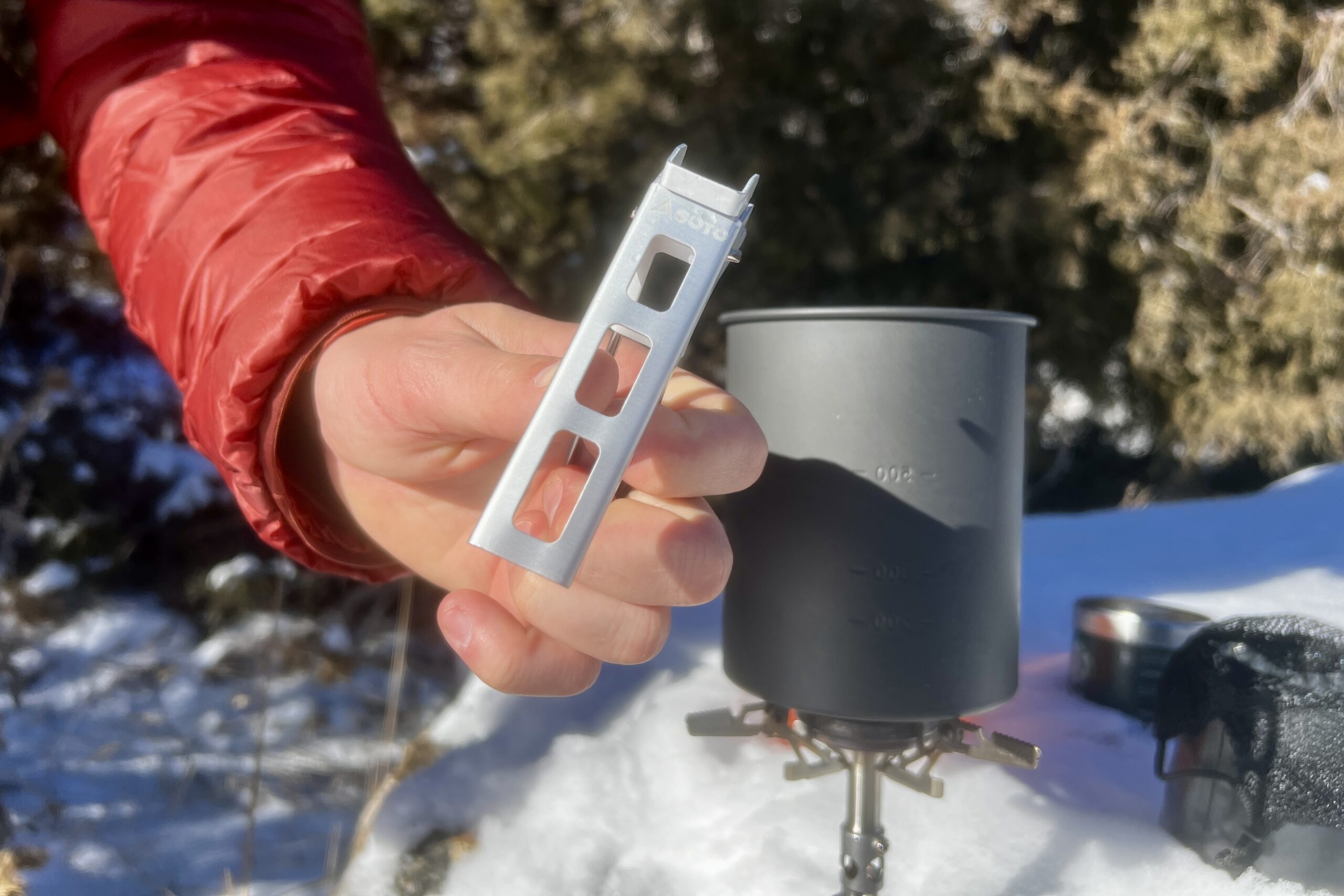 A hand shows the pot lifter of the thermostack combo with the aluminum pot in the background.