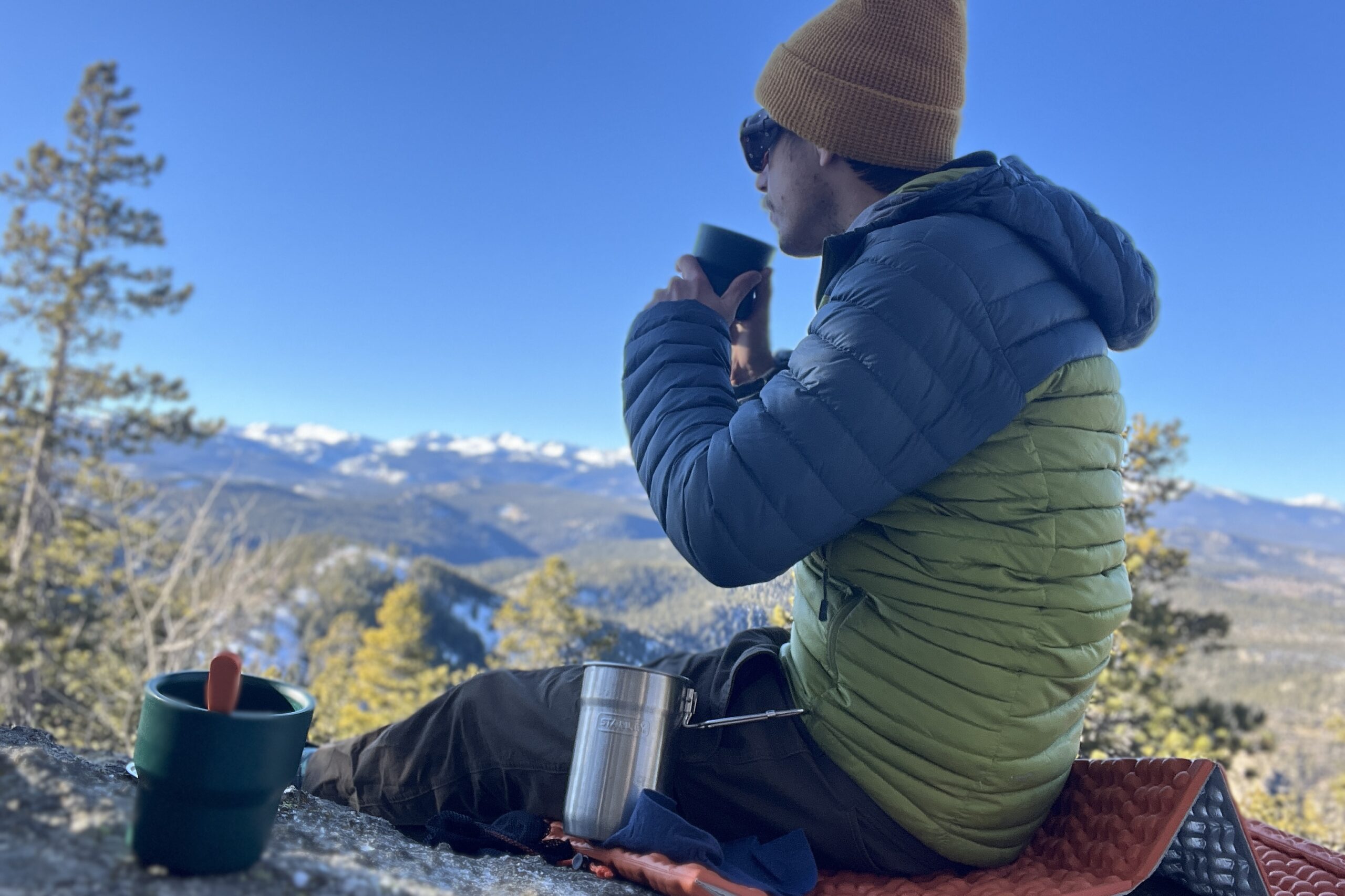 a backpacker drinking from his stanley nesting cup on a cold and sunny morning