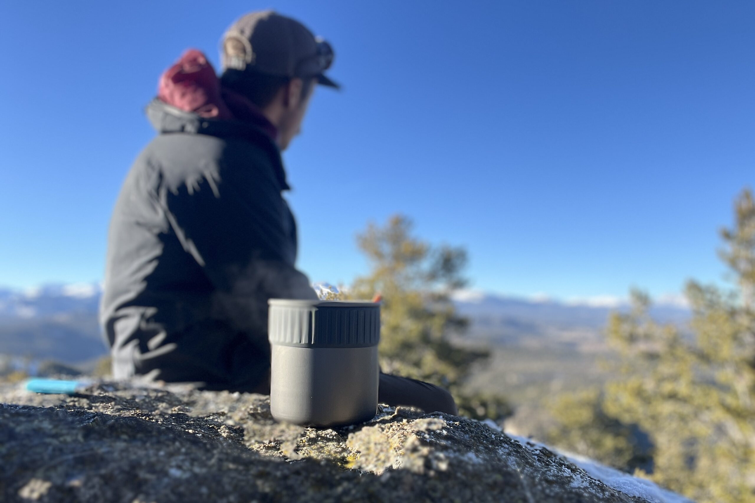 A hiker looks out over a mountain view with the trail mini solo in the foreground.