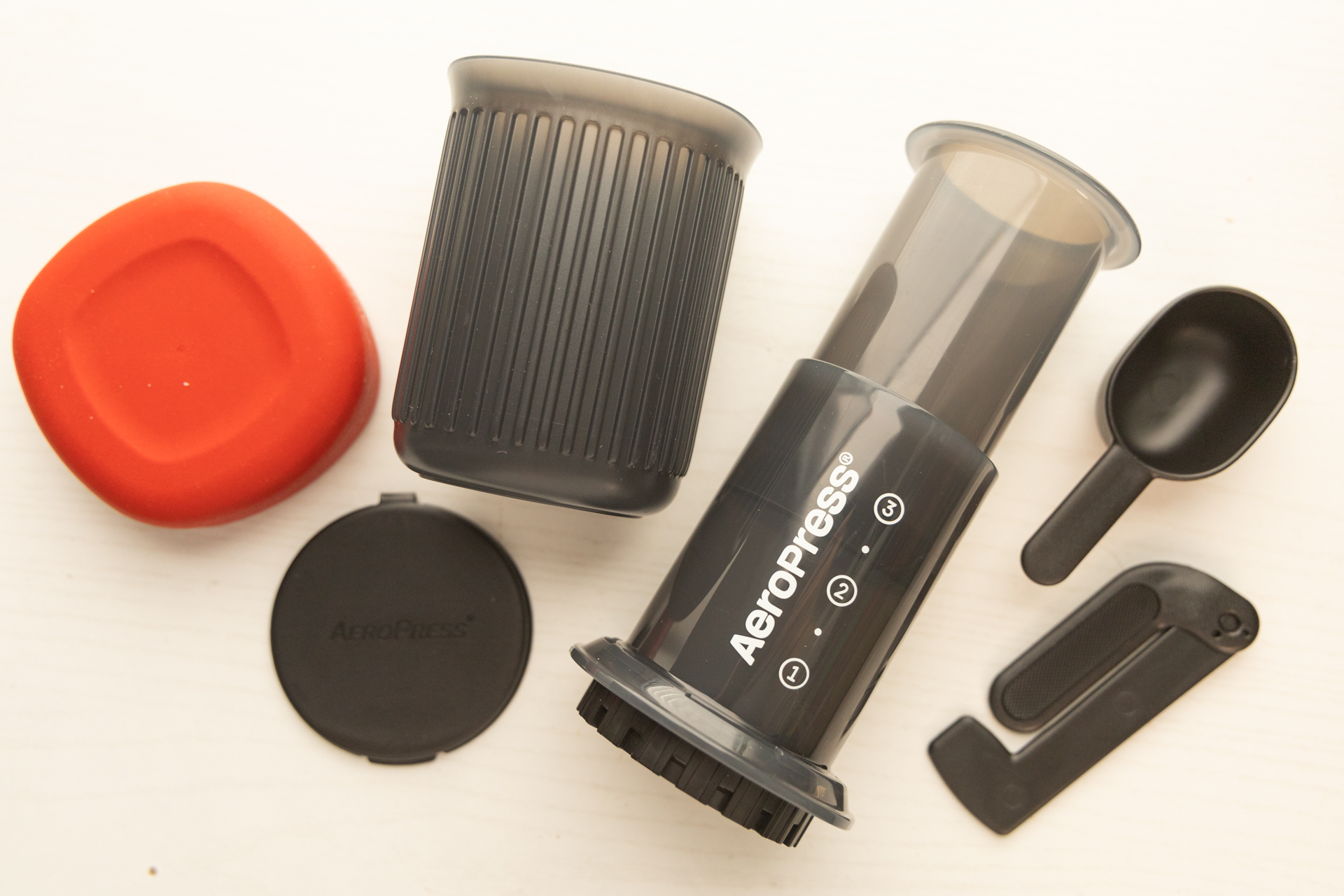 The parts and pieces of the Aeropress Go: Body and plunger, filter keeper, cup and lid, scoop and stirrer.