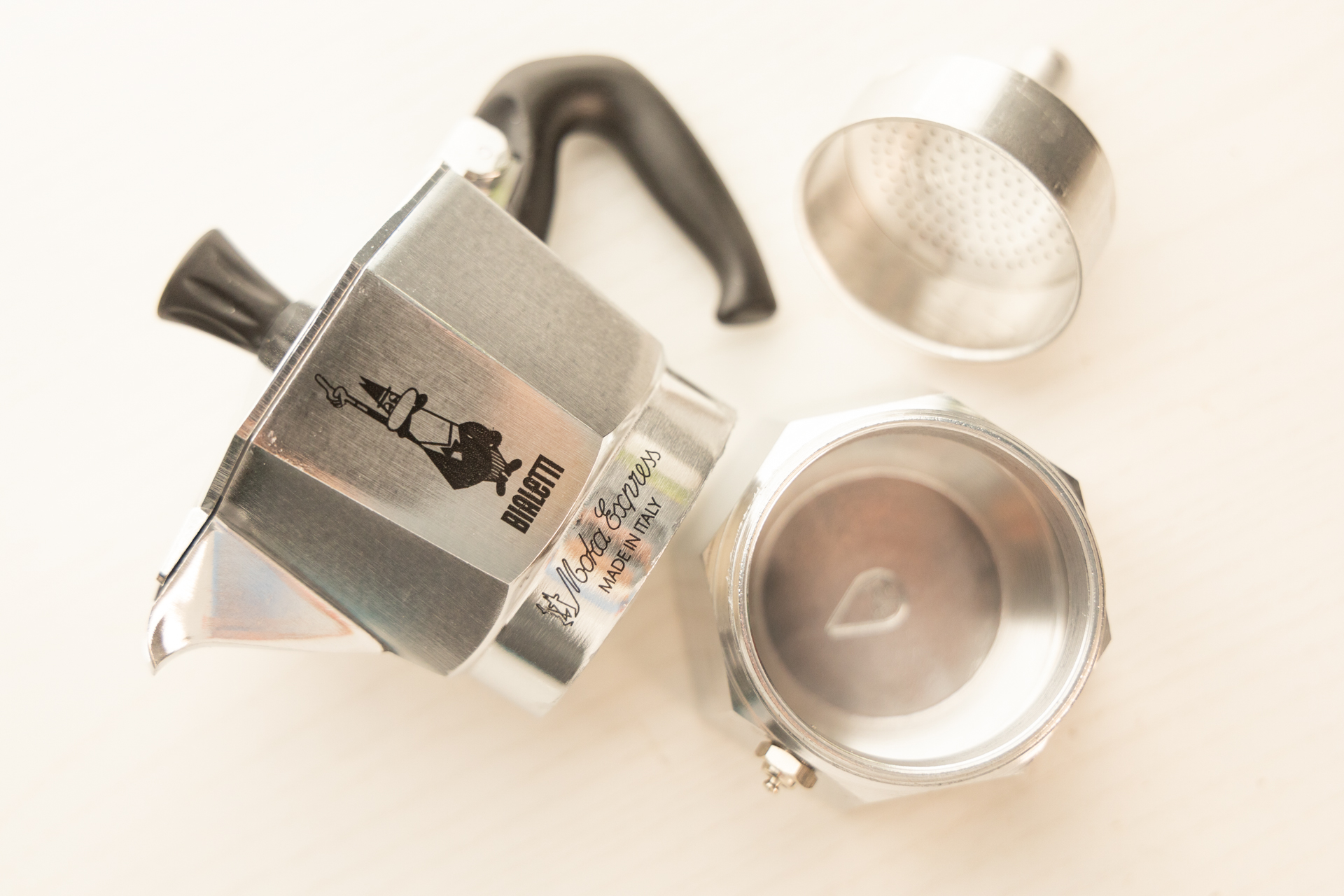 The three parts of the Bialetti Moka Express disassembled: the lower reservoir, filter basket, and upper reservoir.
