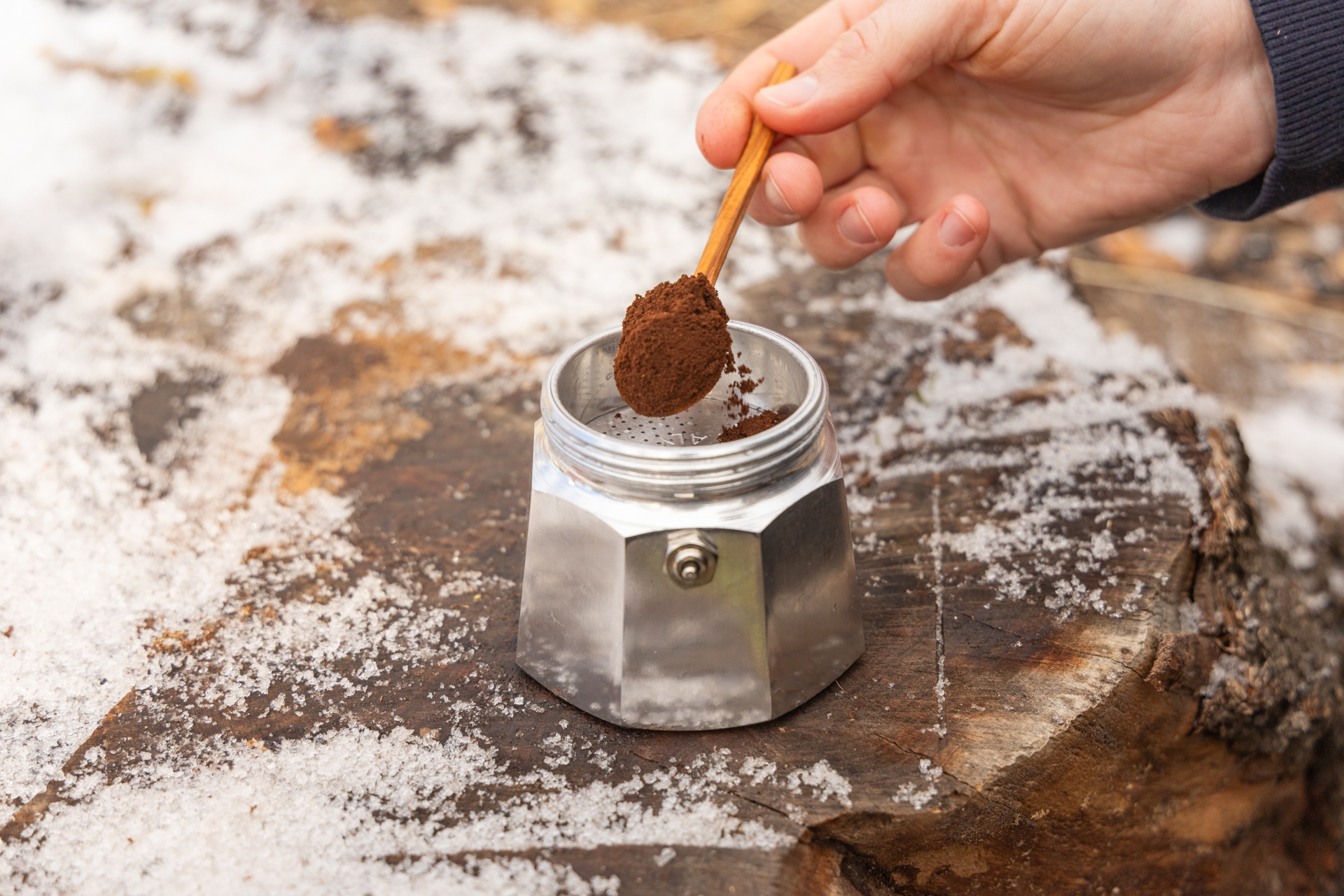 A spoon adds fine coffee grounds to the Bialetti Moka Express.