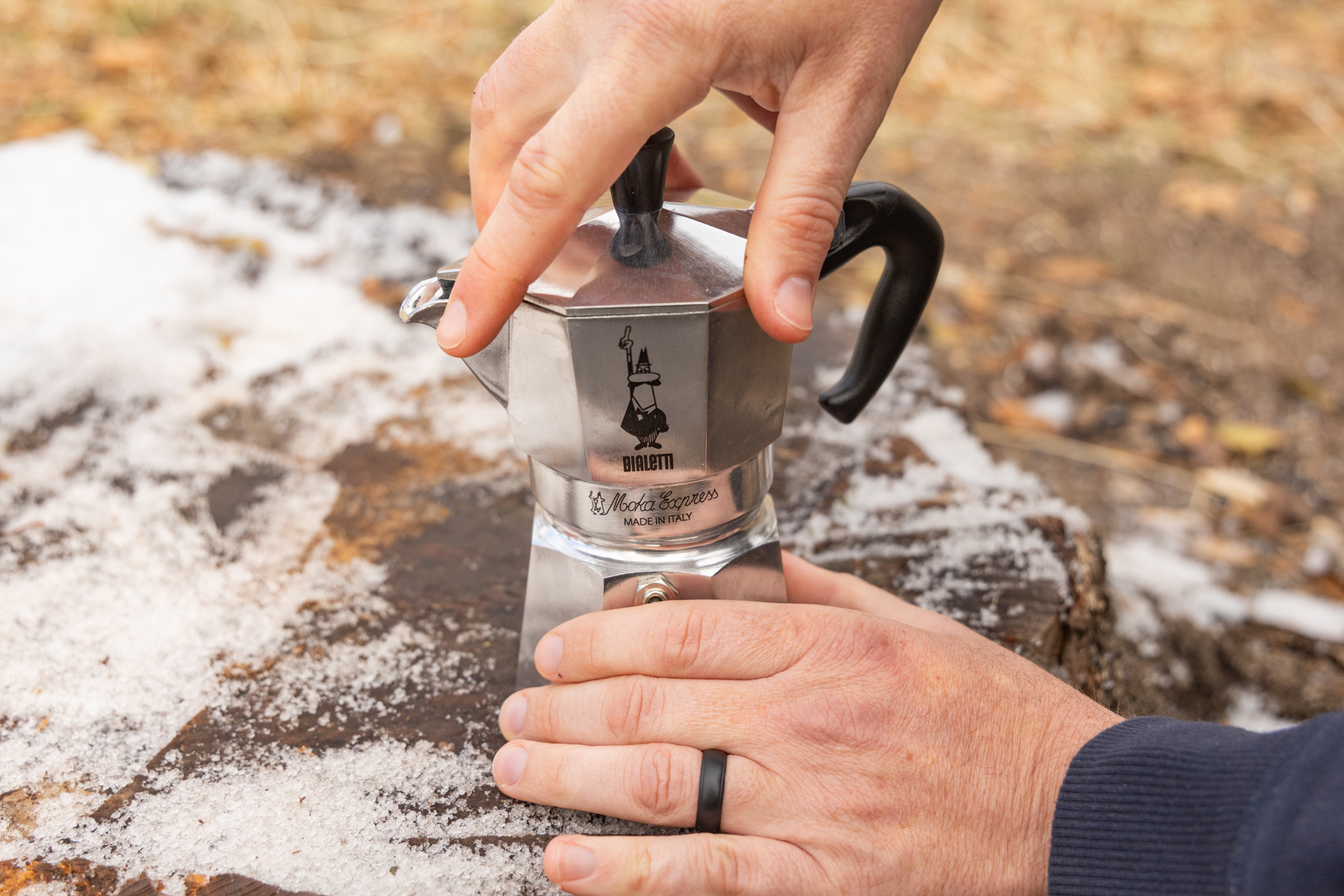 Two hands screw the bottom and top of the Bialetti Moka Express together.