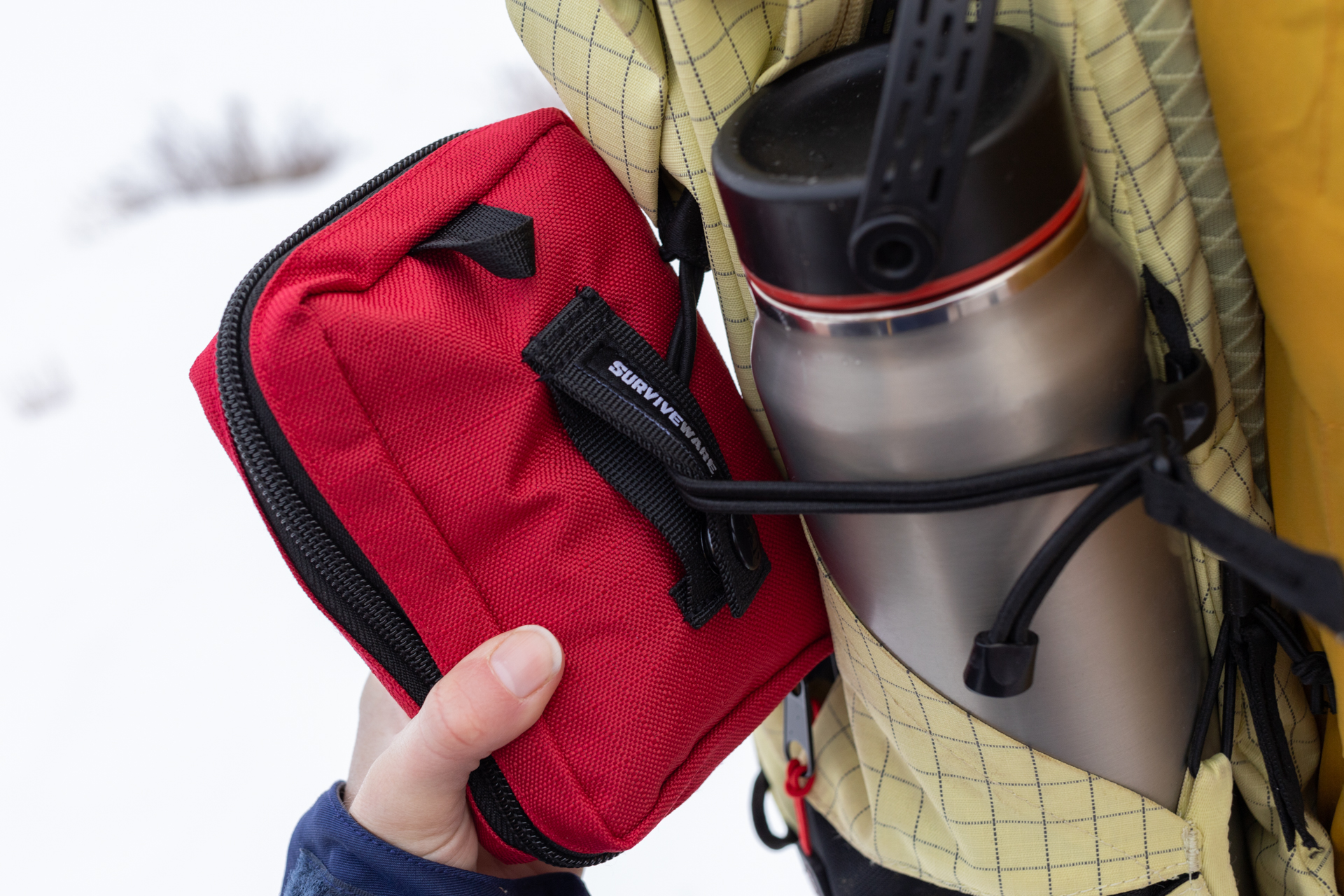 The Surviveware Small looped onto an exterior pack strap.