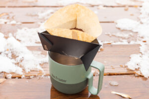 Dry coffee grounds in a filter in the MiiR Pourigami sit atop a mug.