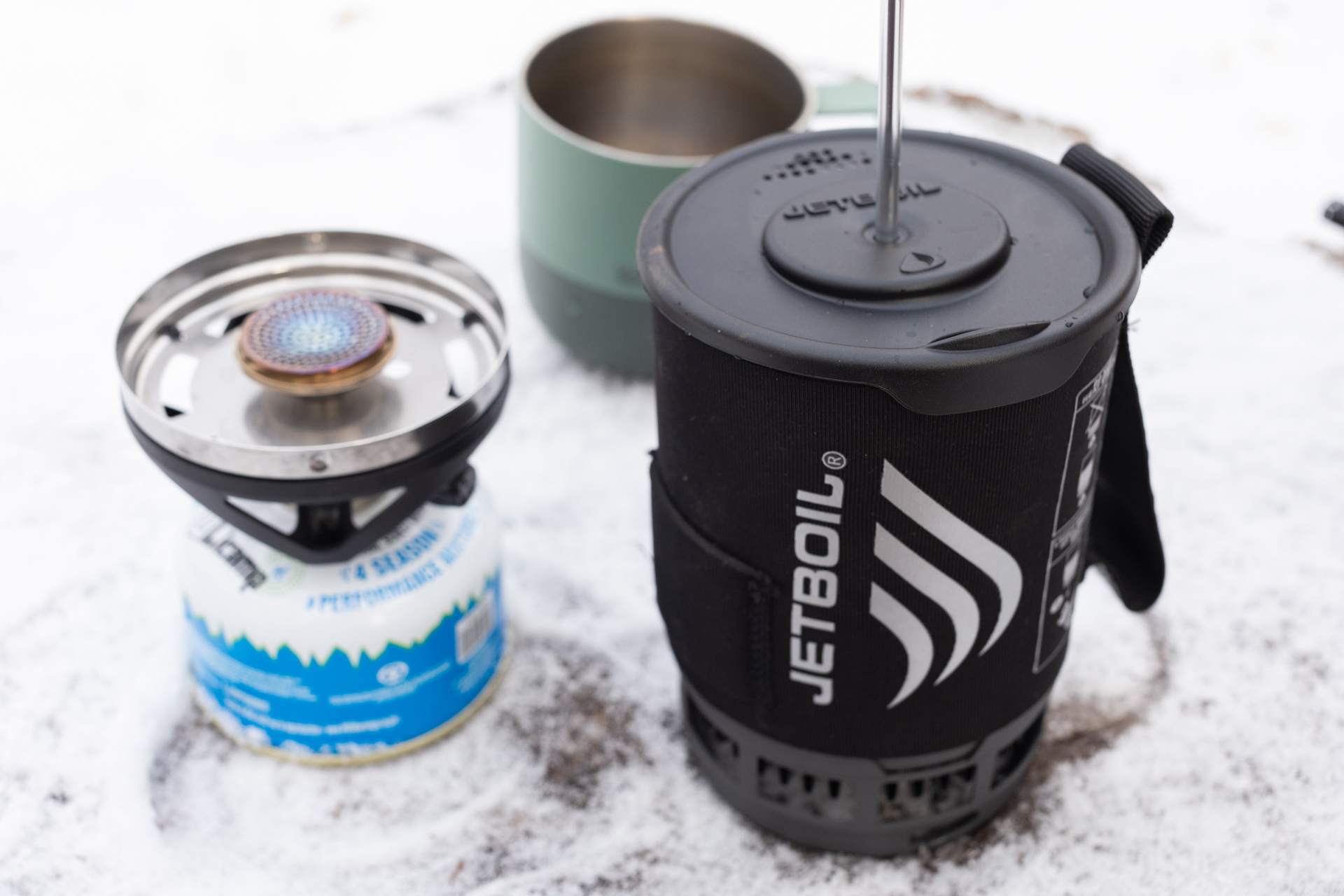 A Jetboil Silicone Coffee Press sits next to a stove waiting to be pressed.