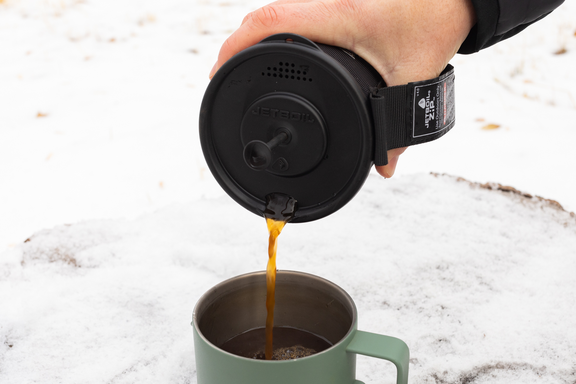 A hand pour coffee into a mug from a Jetboil.