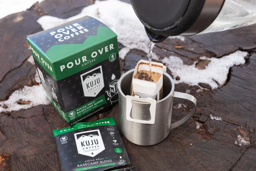Water pours into a Kuju coffee pouch sitting in a mug.