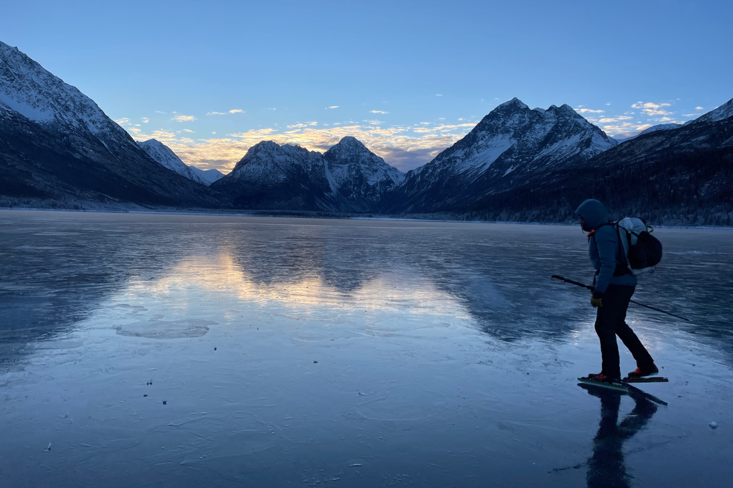 A man ice skates at sunrise with a mountain view