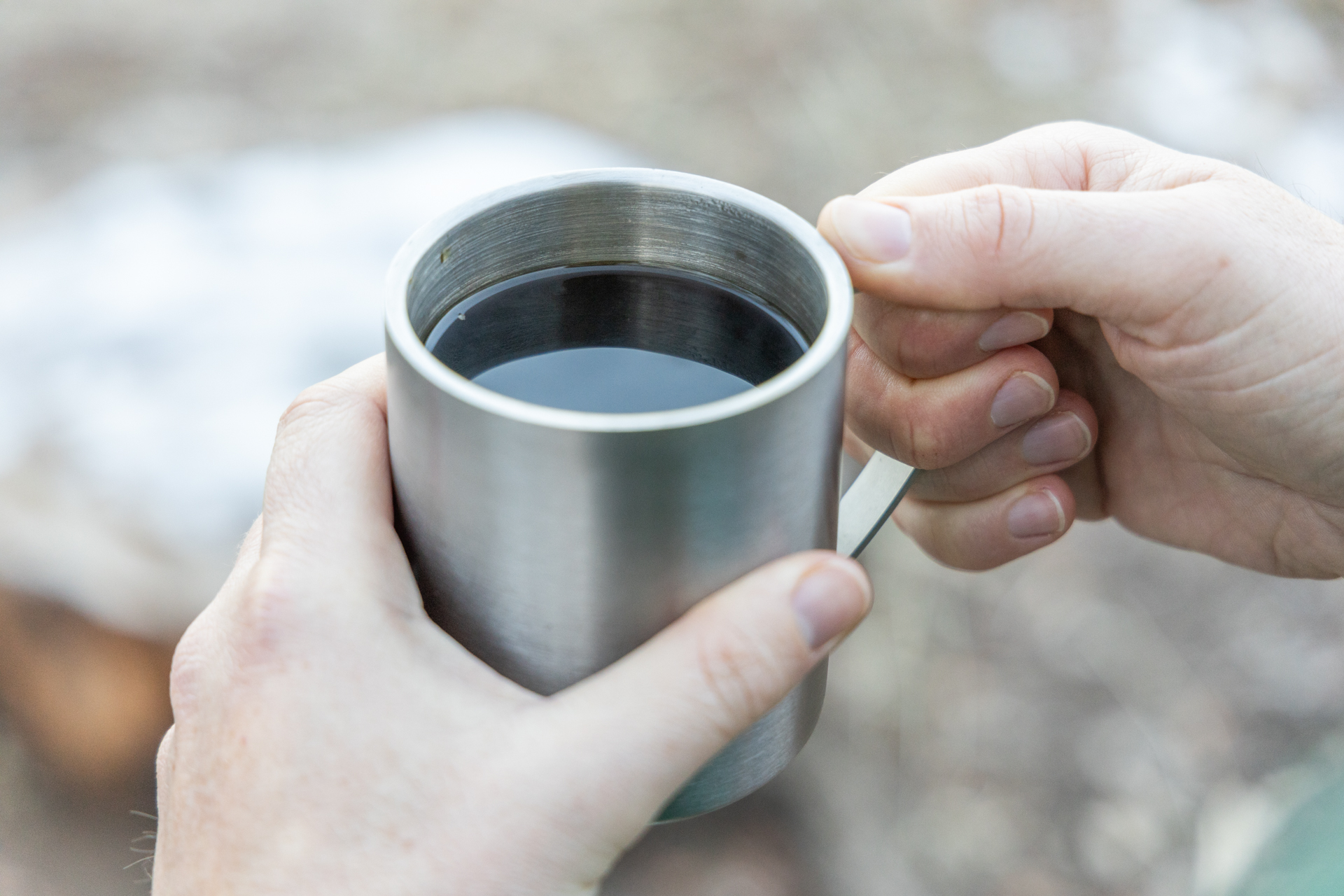 A hand holds a mug of coffee.
