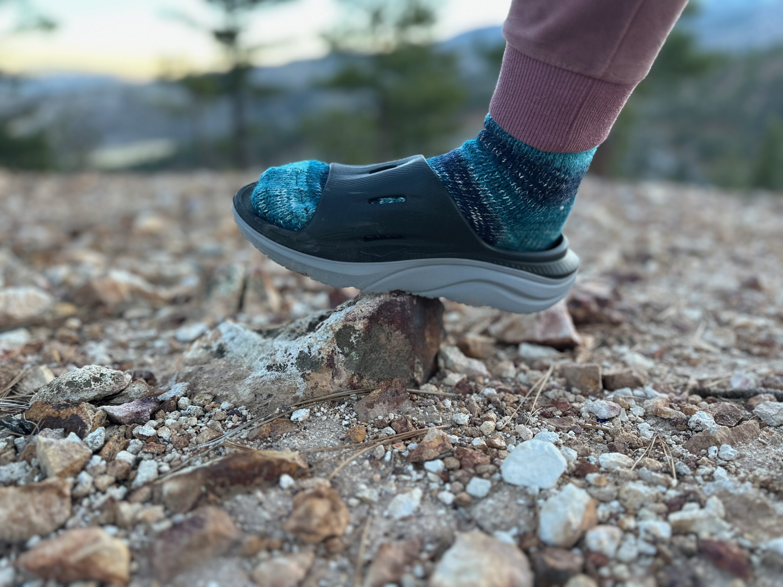 the HOKA ORA Recovery 3 Slides walking on a sharp rock in the high desert landscape