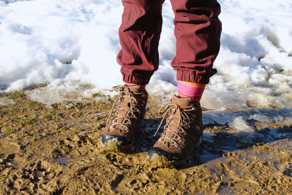 Hiker wearing the Women’s Oboz Bridger WP and standing on a muddy part of the trail
