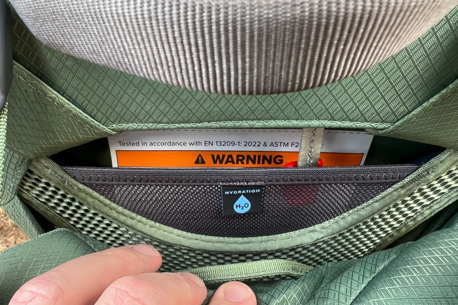 A view of the hydration sleeve compartment on the Osprey Poco Premium, with clear labeling and a peek inside.