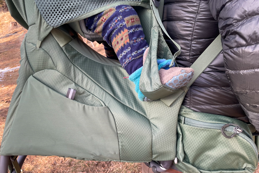 A side view of the Osprey Poco Premium, highlighting the child’s foot stirrup and storage pockets.