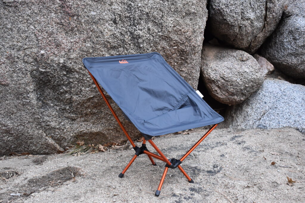 Close up of backpacking chair set up in the sand in front of boulders