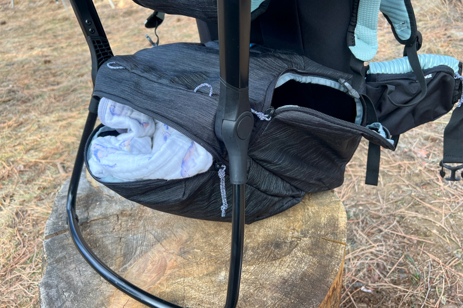 Close-up view of the Thule Sapling's large lower zippered storage compartment with a soft blanket partially packed inside.