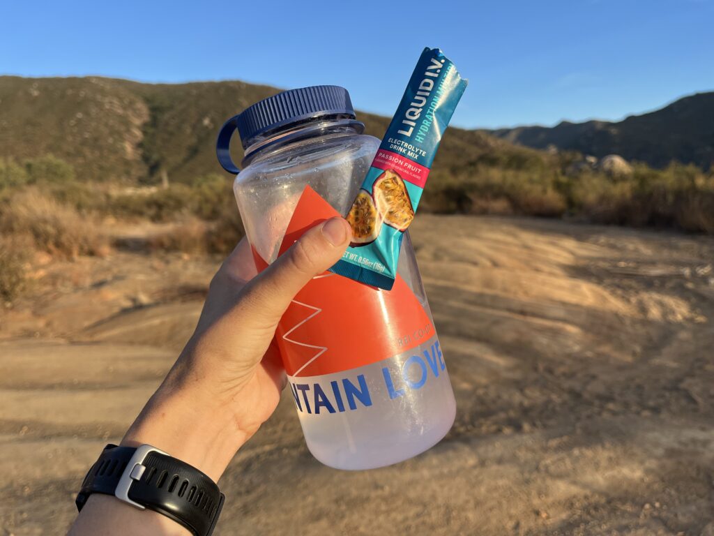 Liquid I.V. mixed into a water bottle with mountains in background