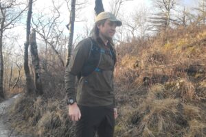 A man stands on a trail showing a GPS watch.