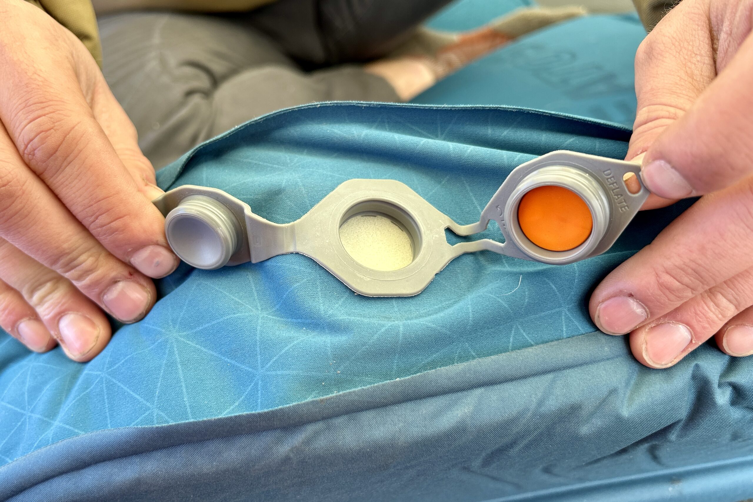 Close-up image of the intake valve with two caps on a camping mattress.