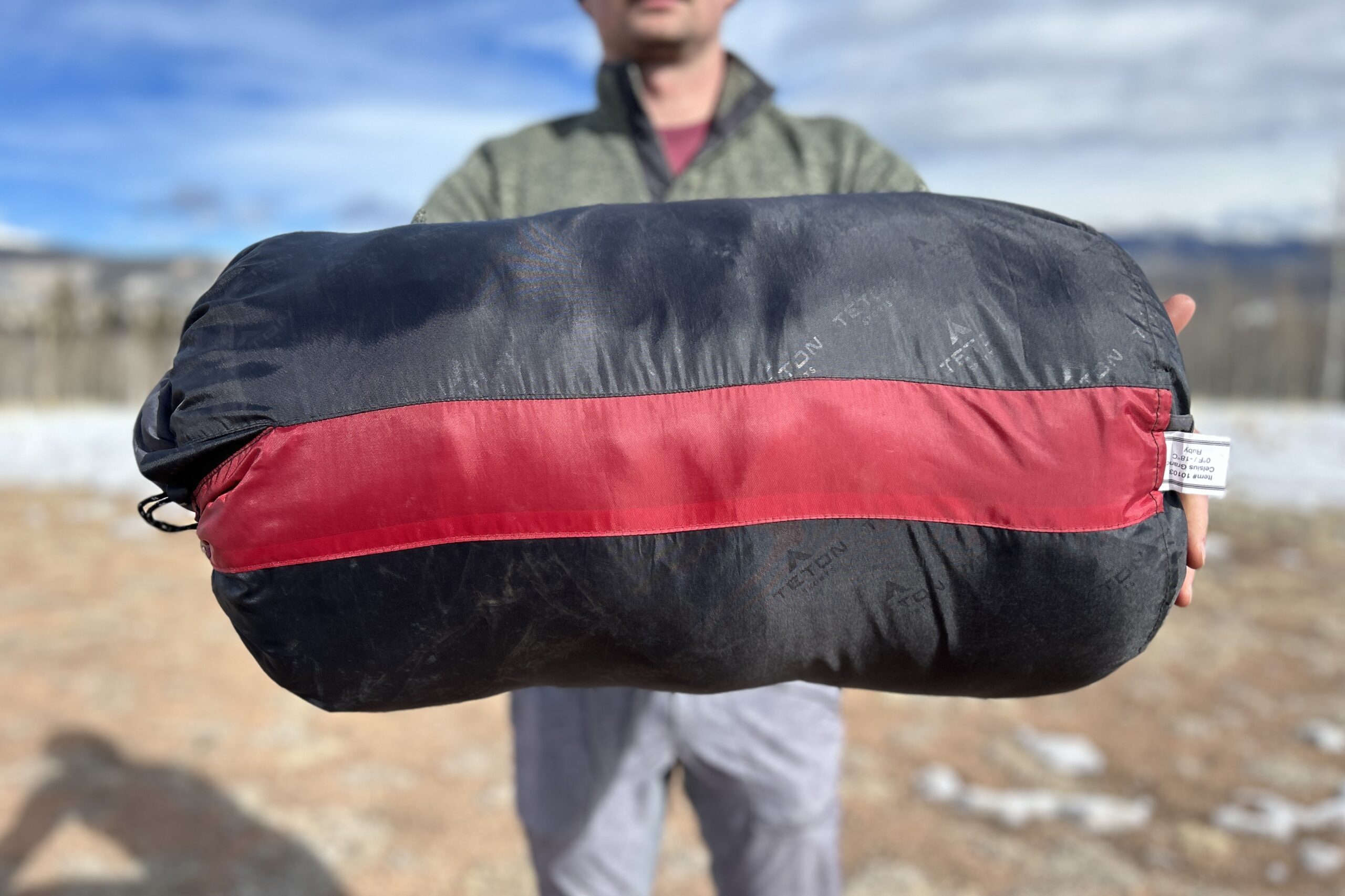 Close-up image of the side of a sleeping bag held up by someone longways.