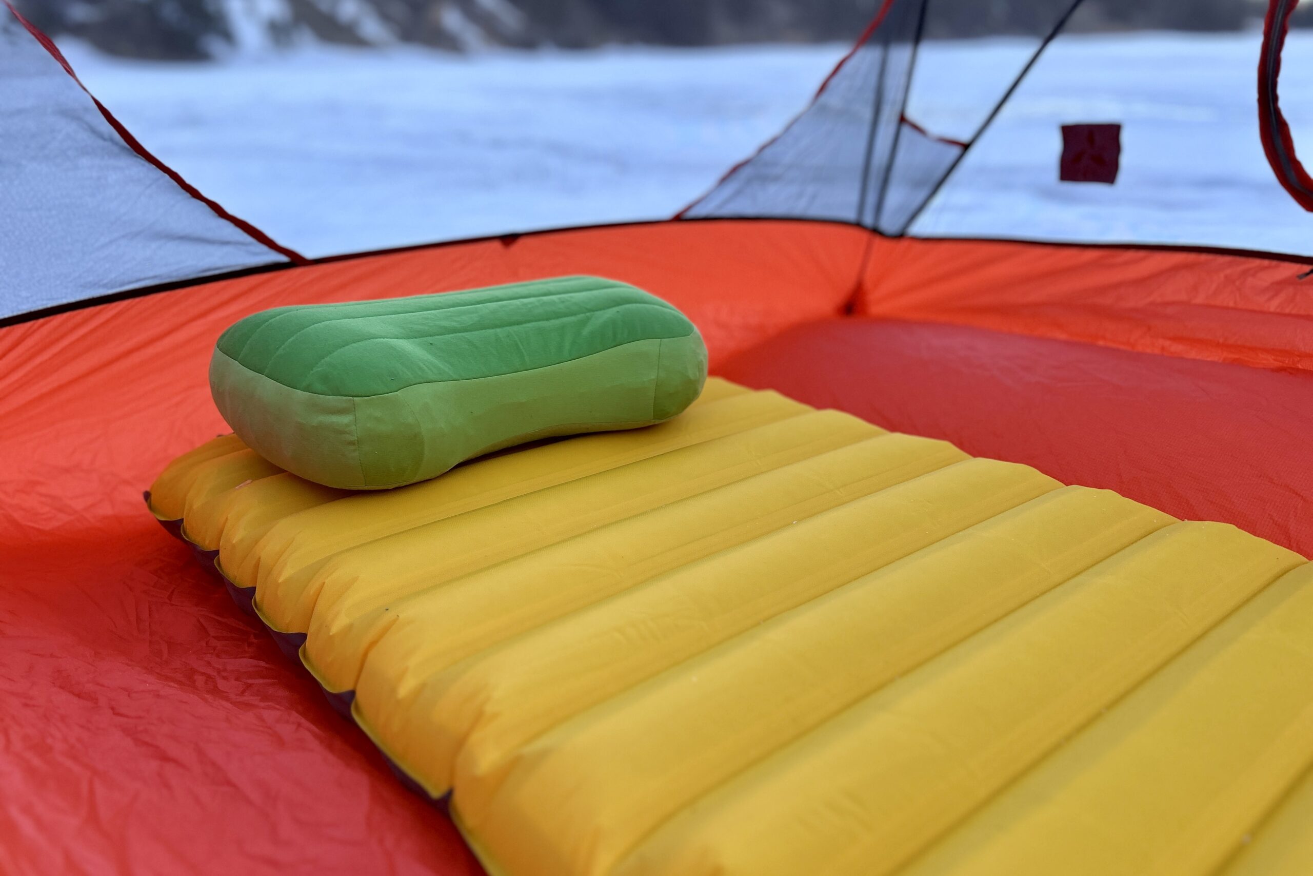 A camping sleeping pad in a tent with a camping sleeping pillow.