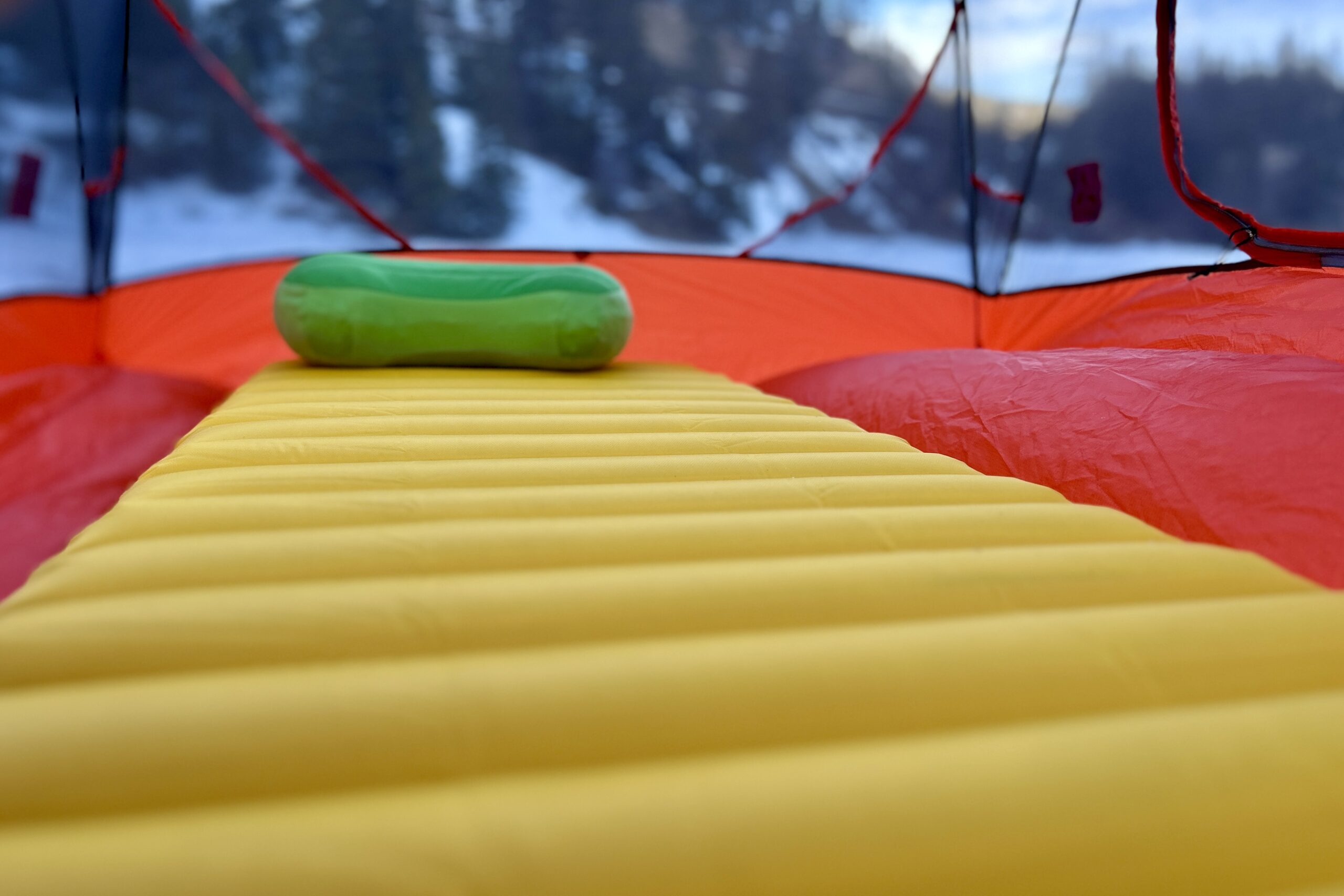 Close-up image of the wide, thick baffles of a camping sleeping pad inside of a tent with a backpacking pillow at the top.