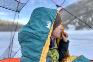 Close up image of a man in a sleeping bag with the hood up over his head.
