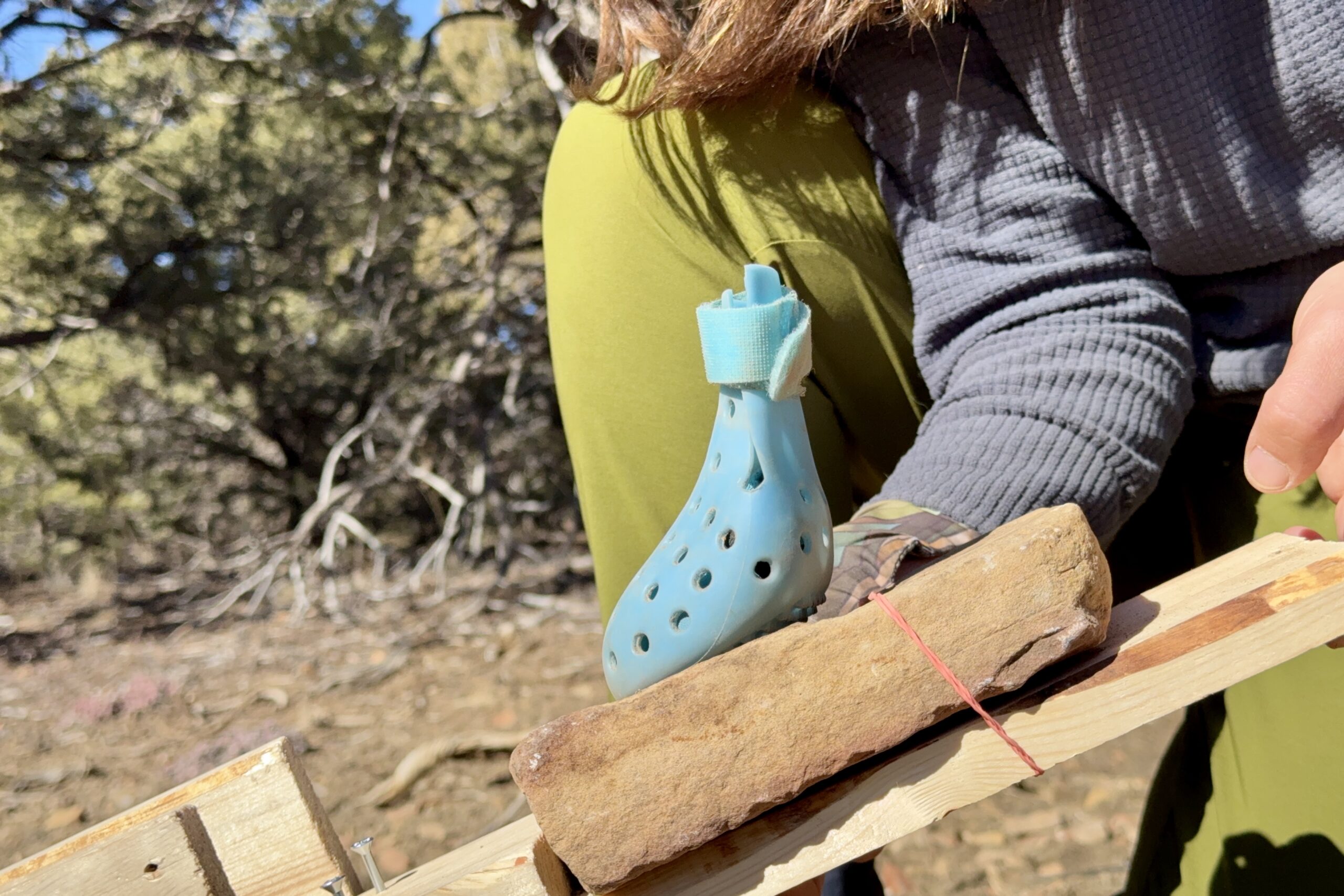 Close up picture of a WagWellies boot on the rock from the traction device. A hand is holding up the board that the rock balances on.