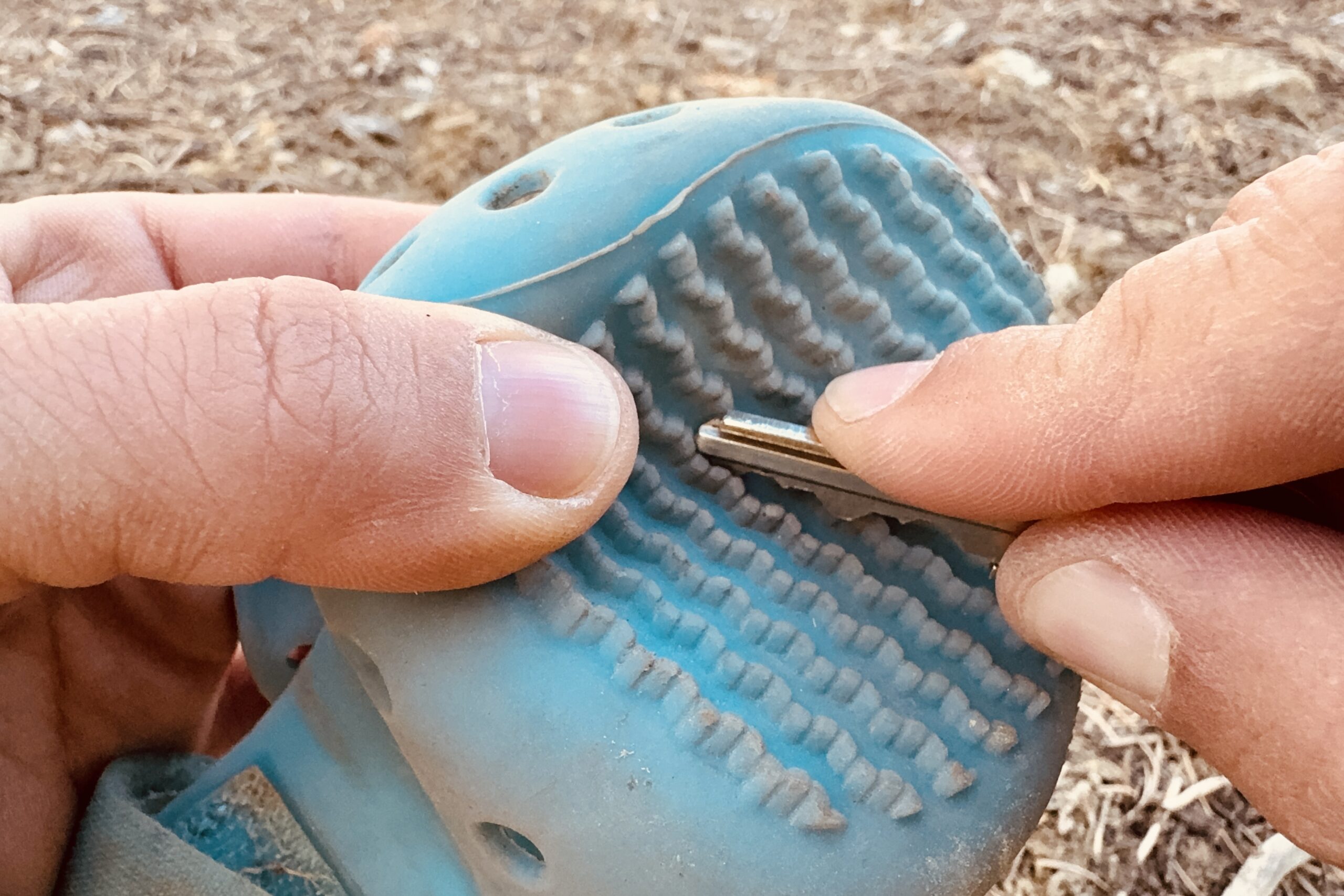 A close up of a hand scraping a WagWellies boot with a house key.