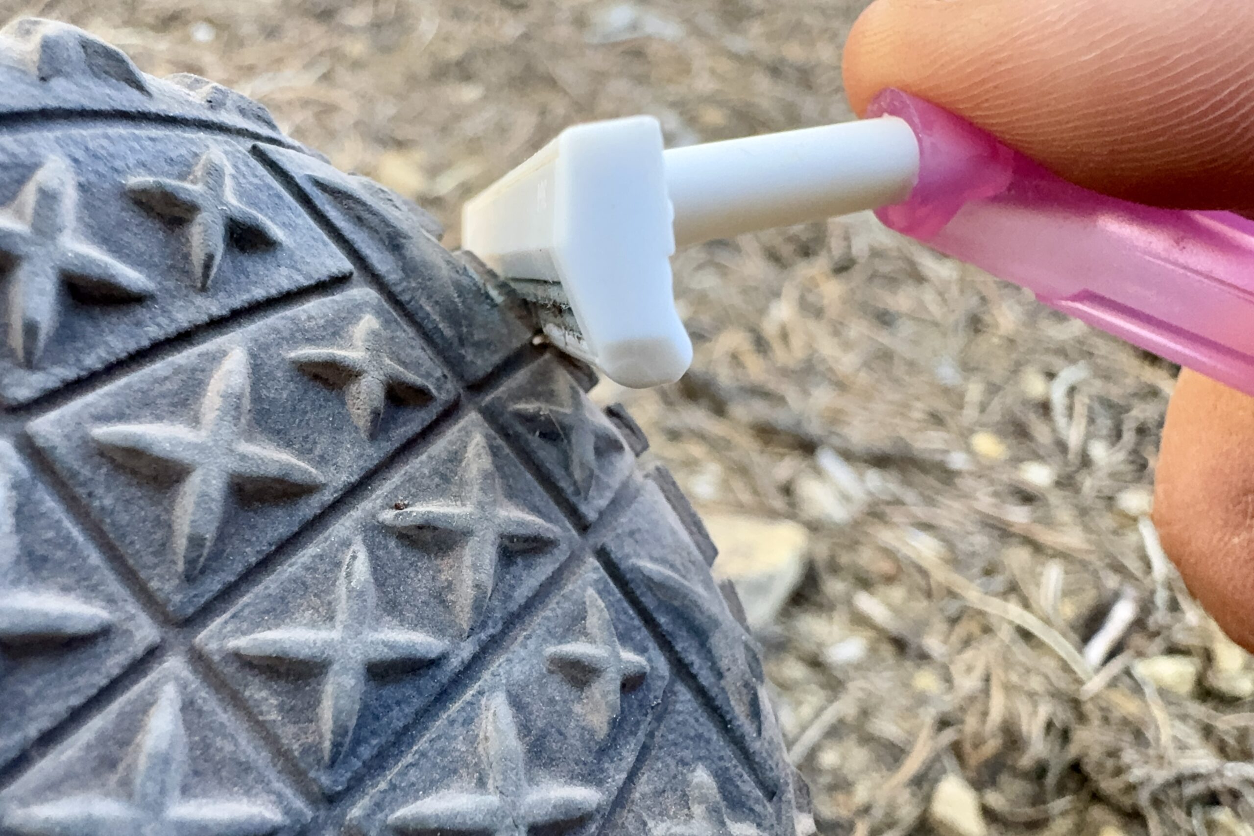Close up of a razor being dragged across the tread of a Ruffwear boot.