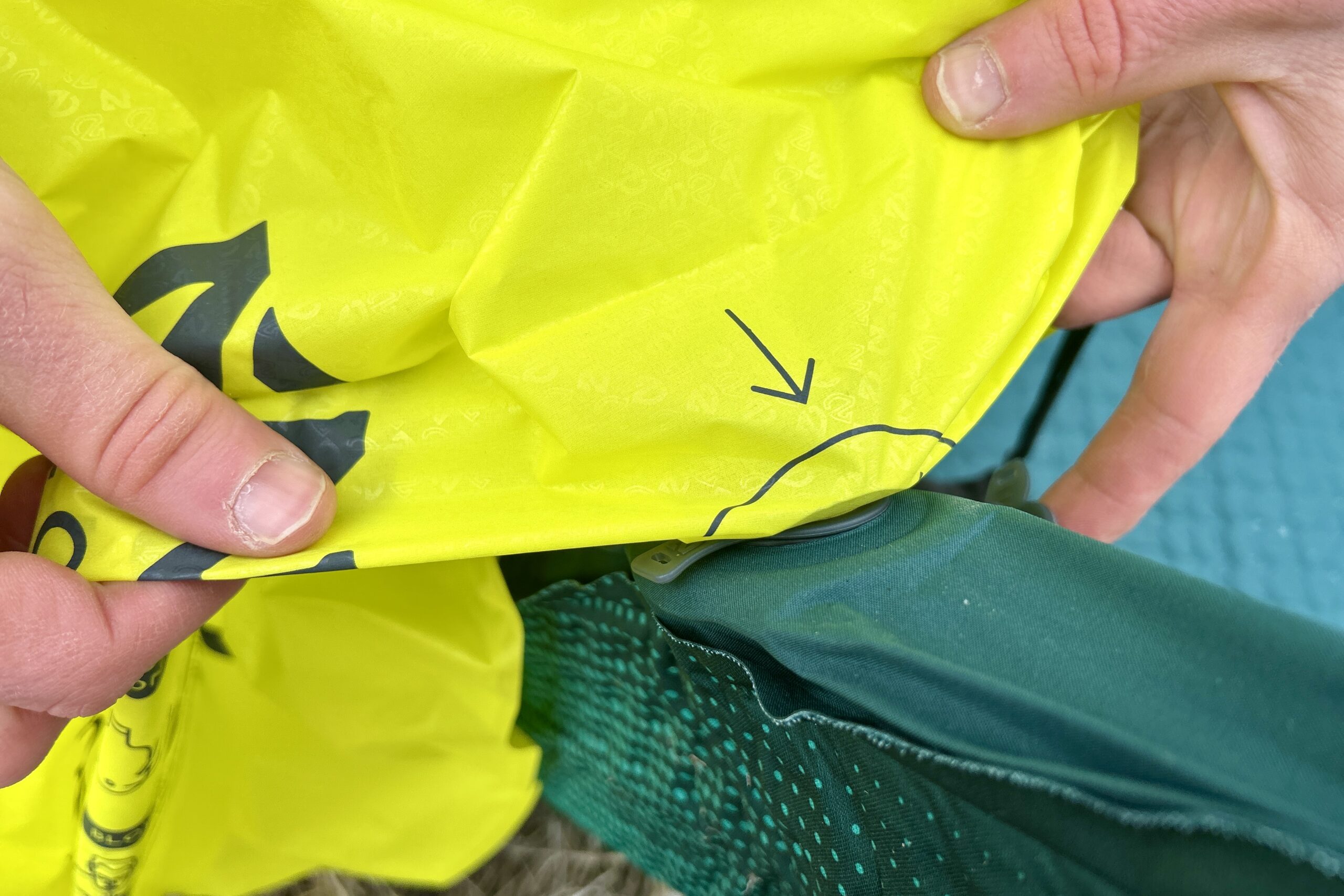 Close-up image of two hands holding a stuff sack attached to the nozzle of a mattress.