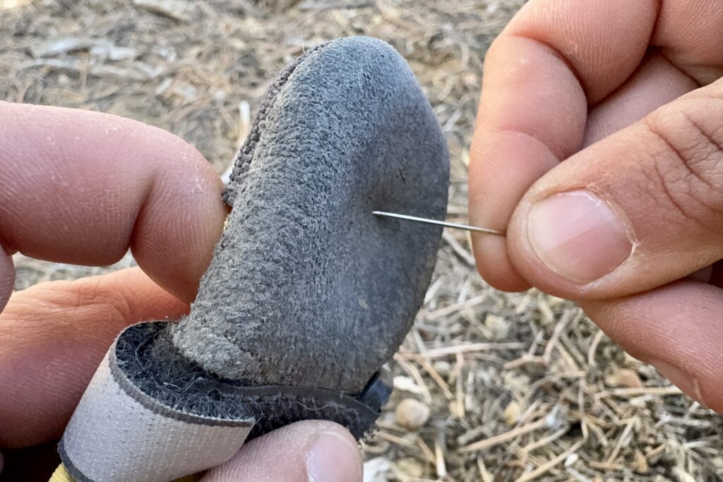 Close up of a Muttluks boot being poked with a sewing needle.