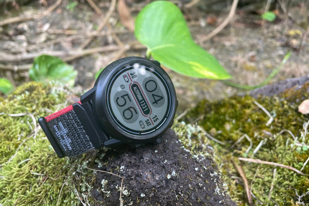 A watch sits on a mossy rock.