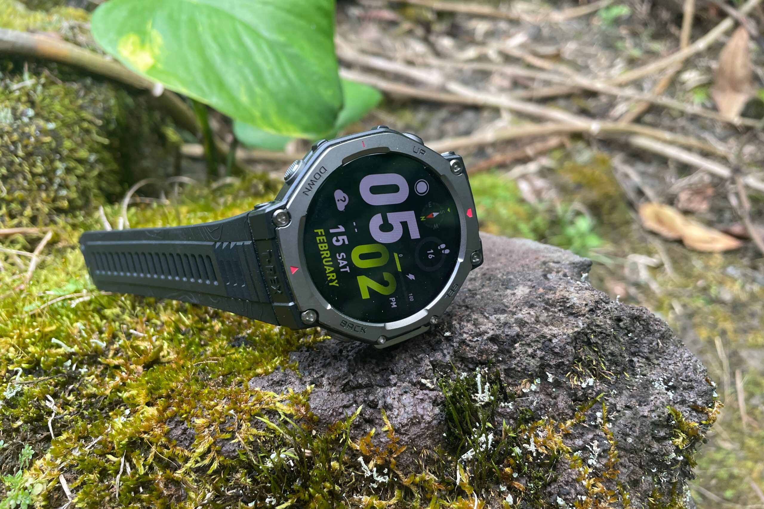 A GPS watch rests on a mossy rock.