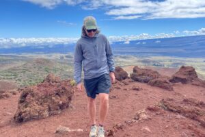 A man walks along an alpine ridge wearing a windbreaker.