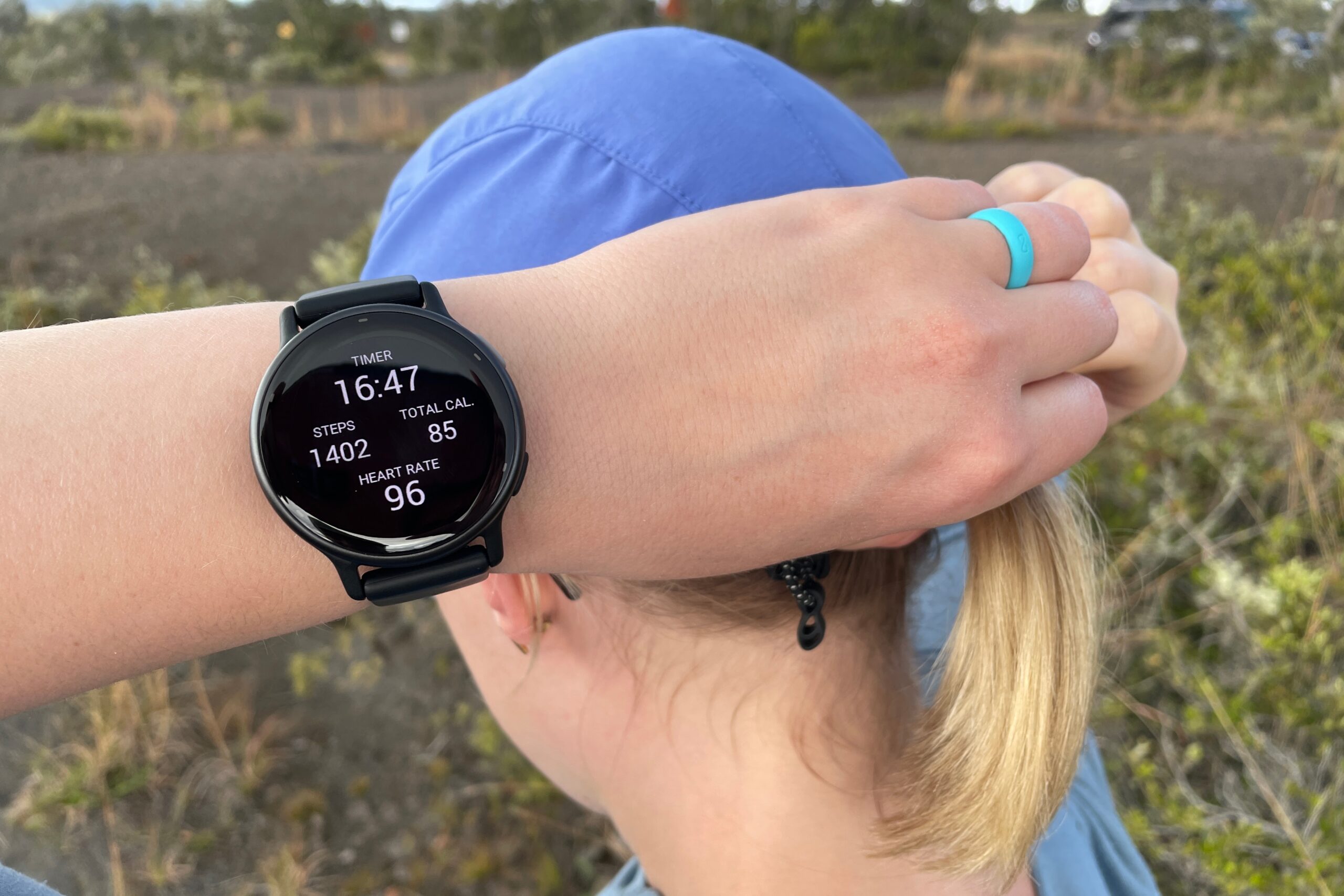 A woman wears a GPS watch while adjusting her hat.