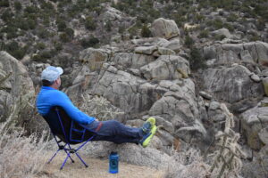 a backpacker stares across a canyon while sitting comfortably in the Moon Lence Portable chair