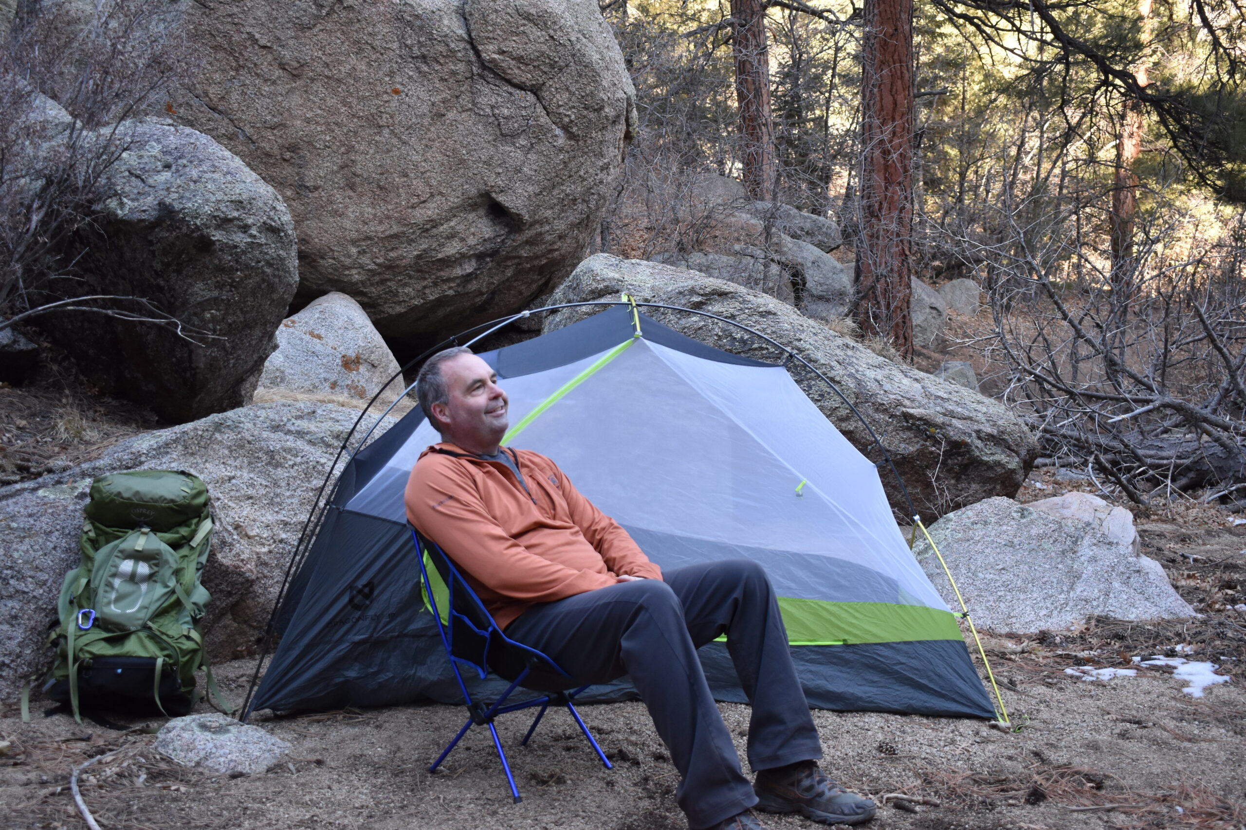 backpacker sitting in the Moon Lence Portable Chair at camp in front of his tent and backpack