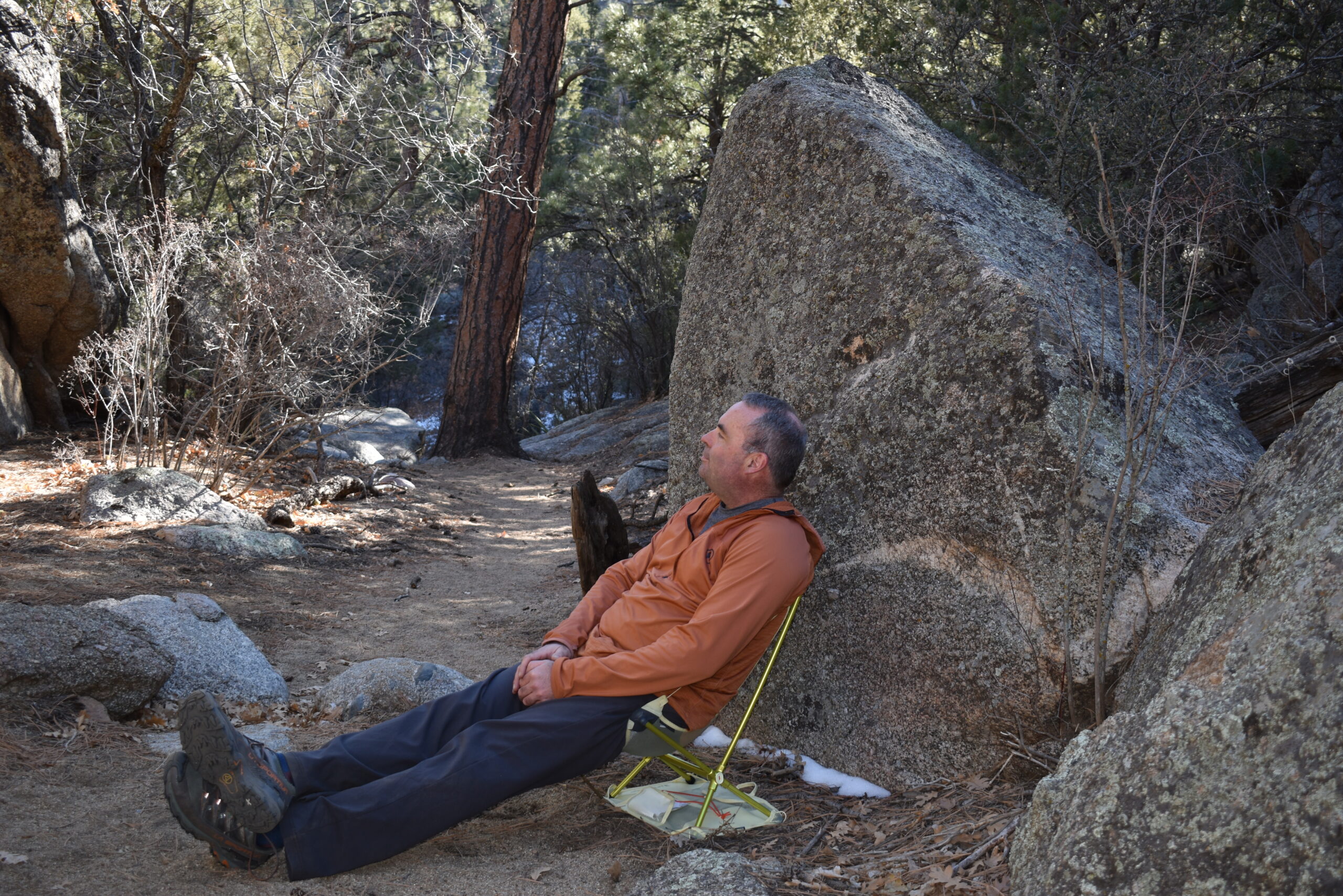 Moonlite chair set up in front of a giant boulder alongside a sandy hiking trail
