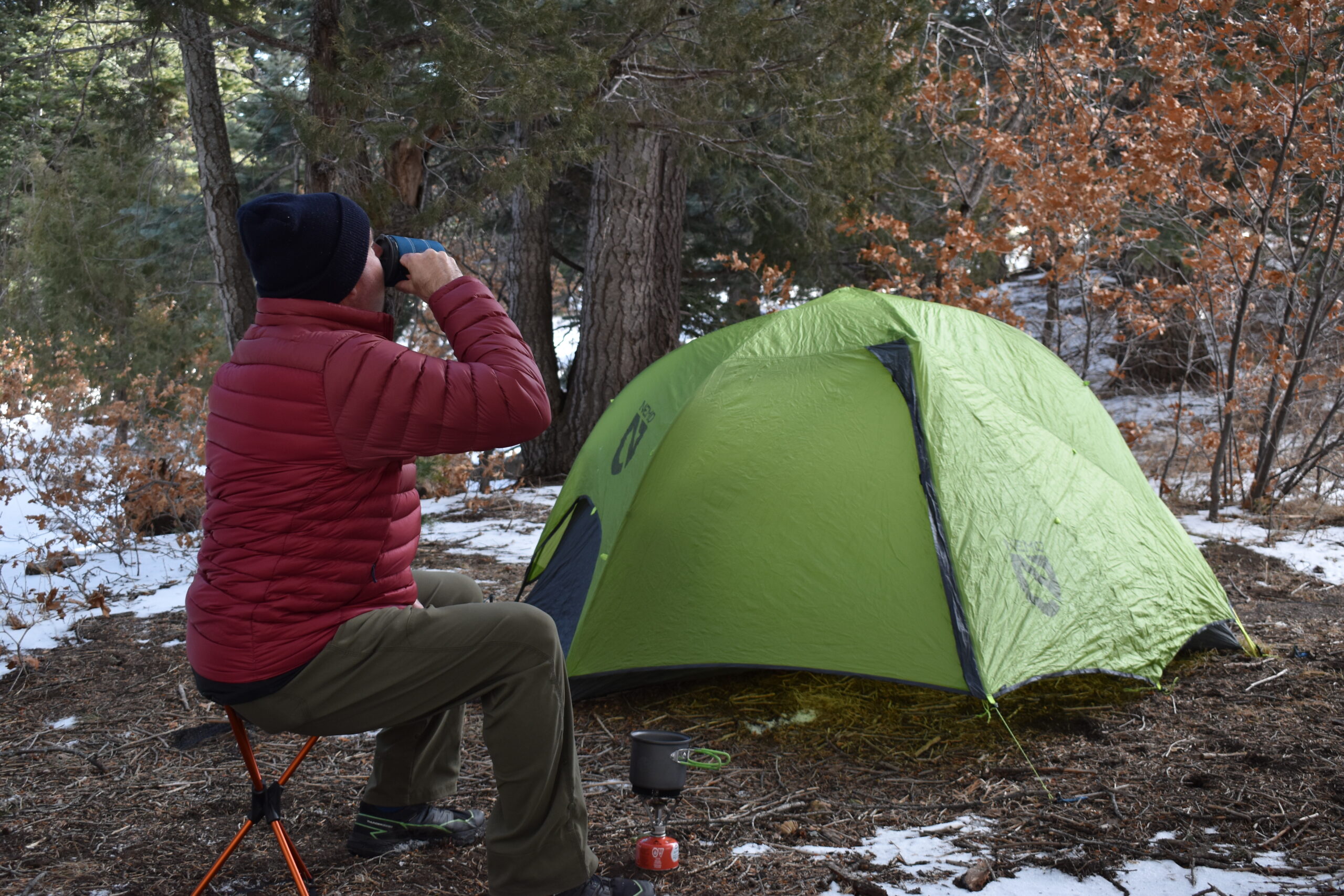 another picture at camp of a backpacker drinking coffee on the Flexlite Air Stool