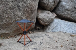 REI stool set up on the stand in front of gray boulders