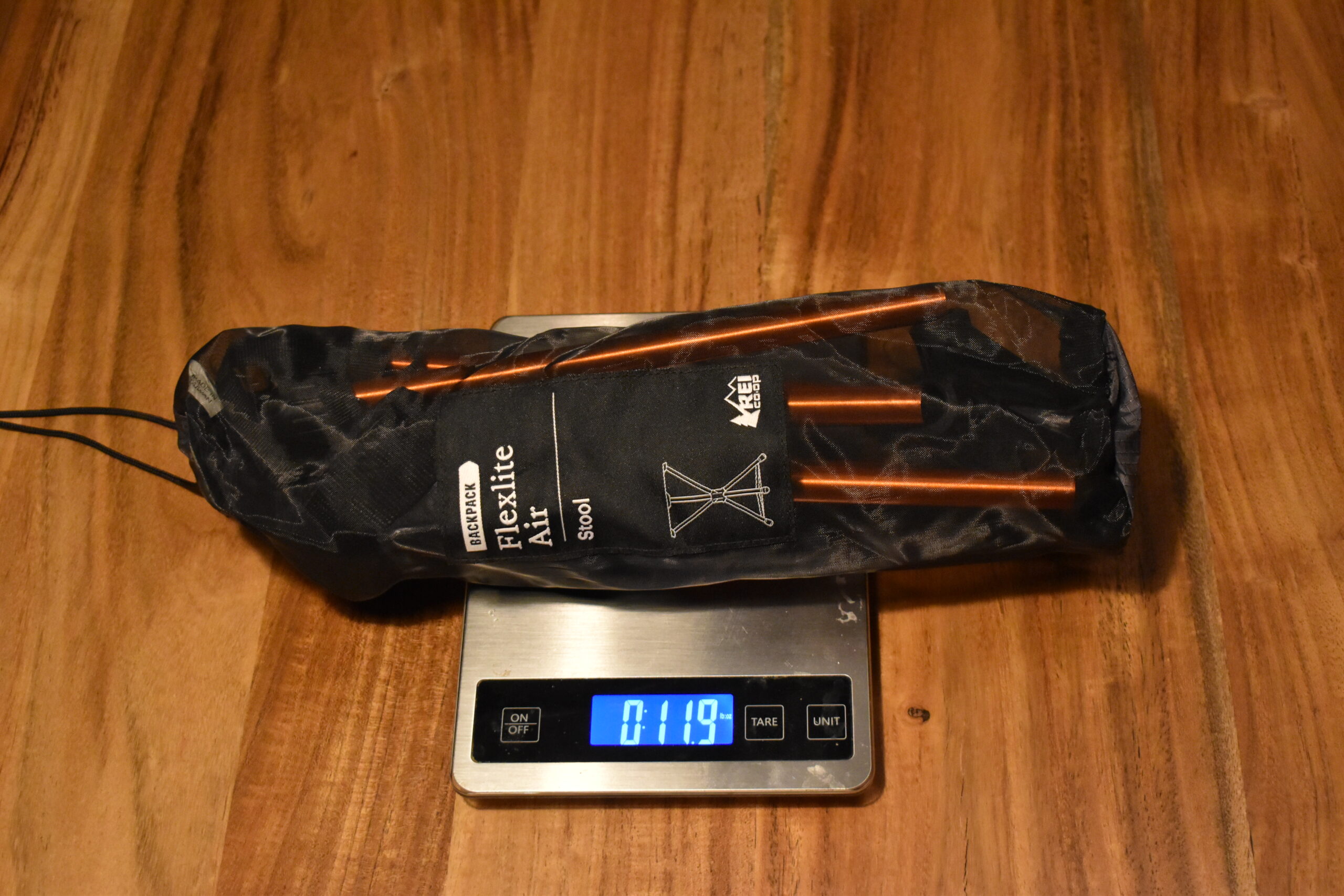 the REI Flexlite Air Stool packed on top of a kitchen scale that reads 12 0z