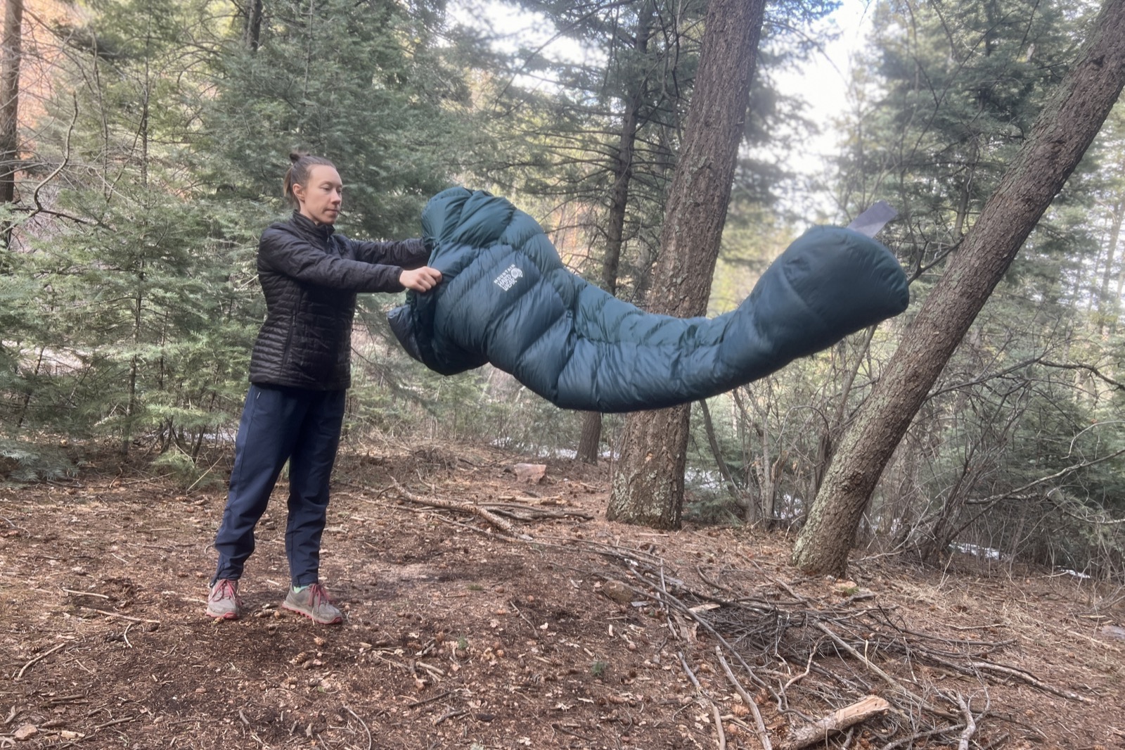A hiker tosses a sleeping bag in the woods