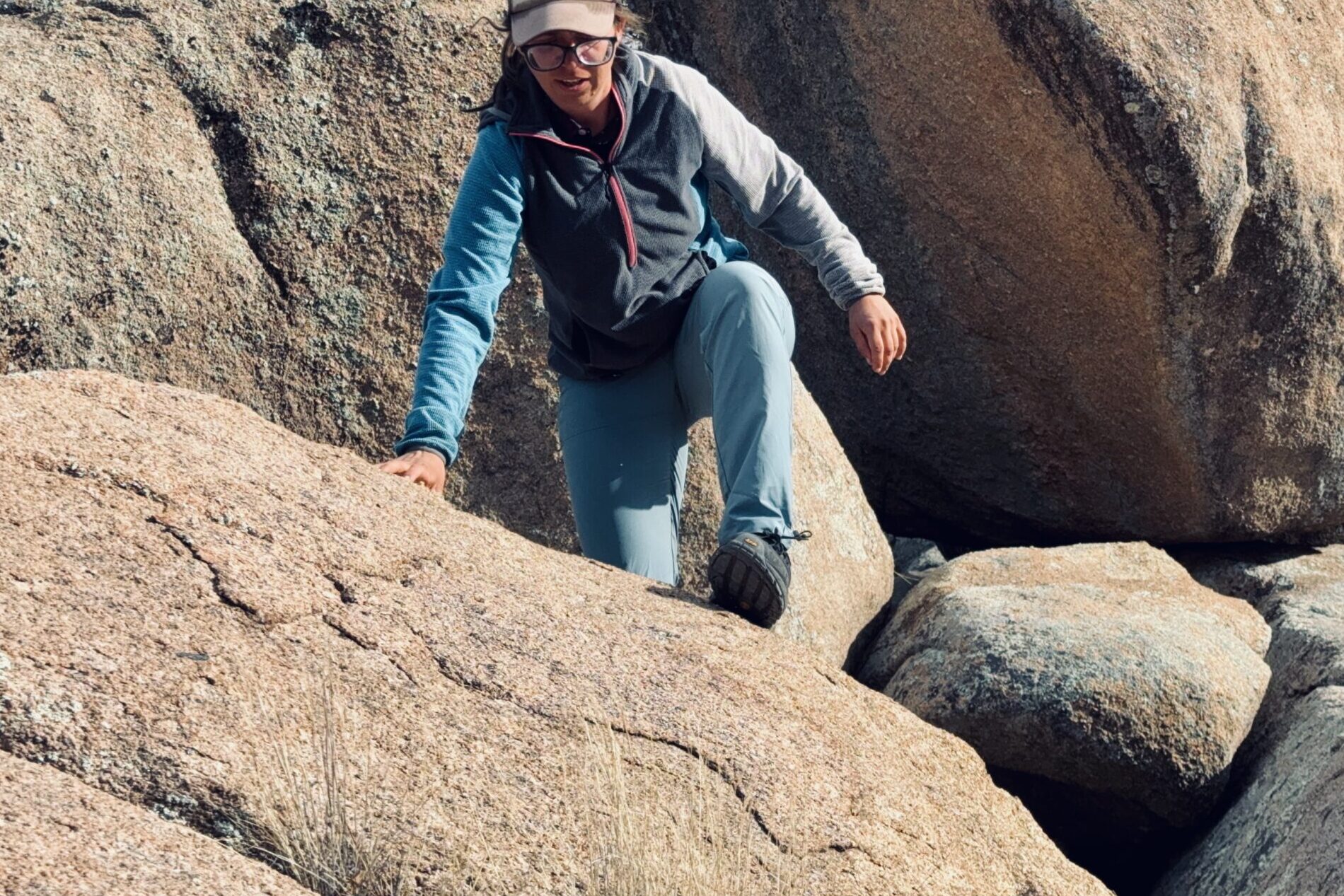 A person wearing the Baleaf pants is climbing up a rock in the woods.