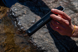 A close up of a hand holding a straw water filter