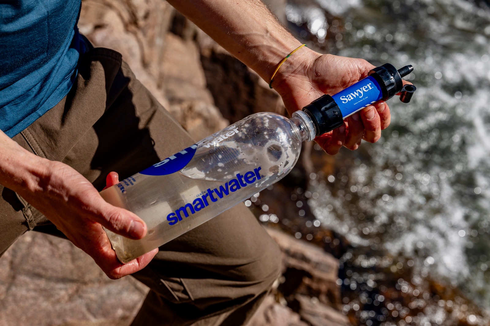 A hiker holds a smartwater bottle with the sawyer mini attached