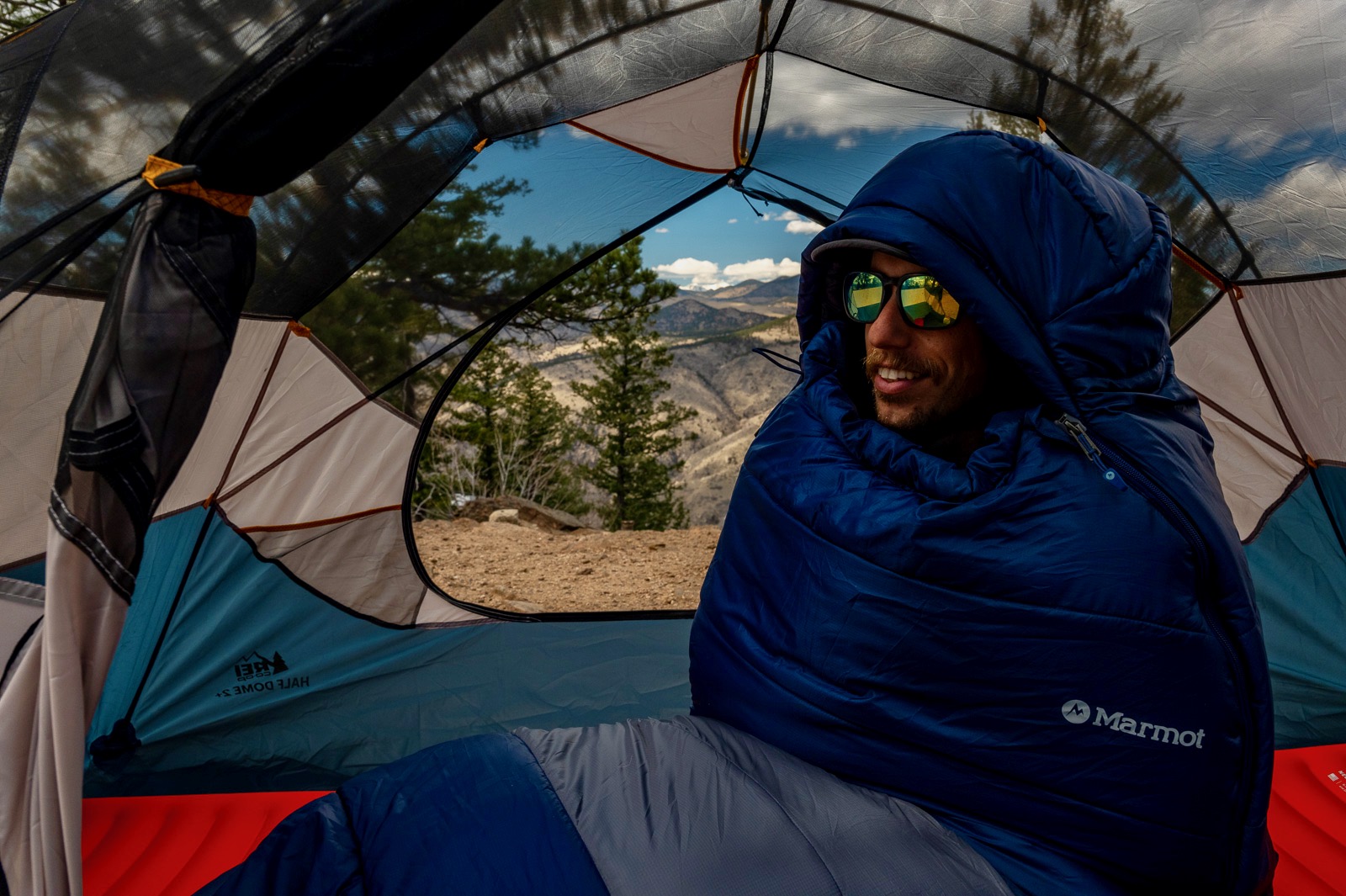 A hiker sits up in a sleeping bag in a tent