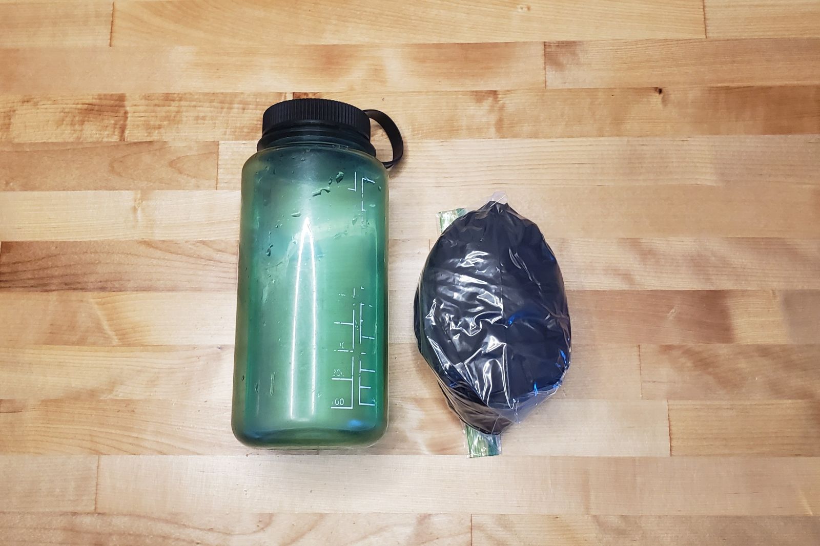 A windbreaker packed into a ball next to a one liter bottle for scale.