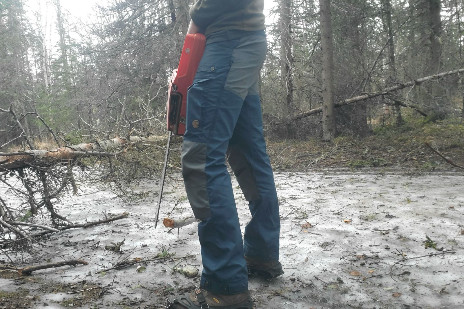 A man works on a trail wearing blue hiking pants.